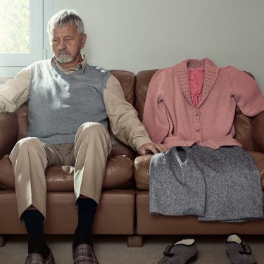 Kampagnenfoto: Mann sitzt vereinsamt auf einem Sofa.