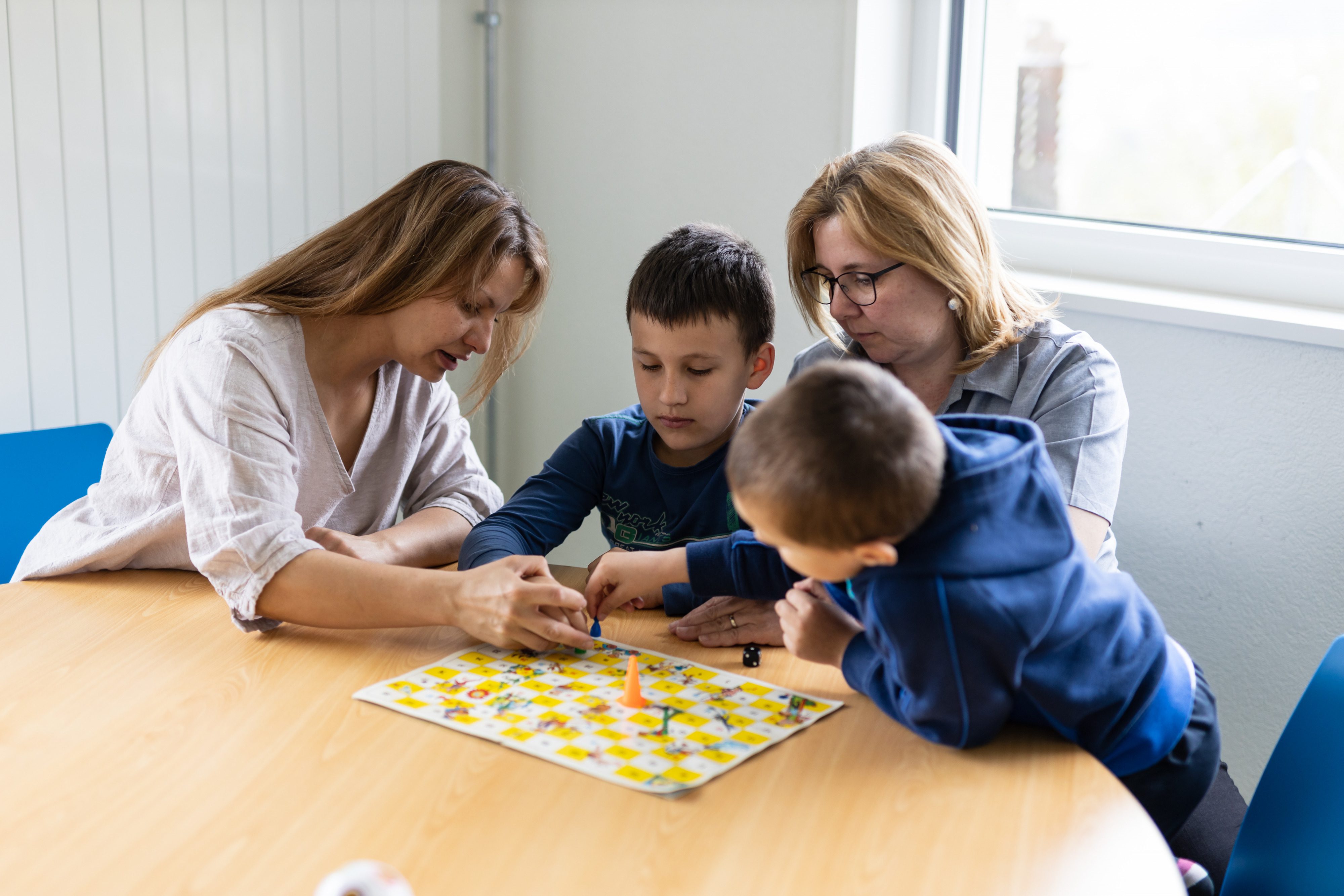 Leiterspiel Kinder Mütter am Tisch spielend