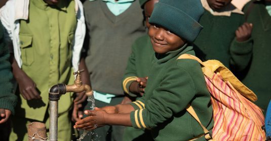 Ein Kind geniesst das frische Trinkwasser in Simbabwe, welches durch das WASH Projekt der Heilsarmee ermöglicht wurde.