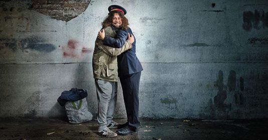 Kampagnenbild: Ein Heilsarmee-Offizier umarmt einen Menschen ohne Obdach.