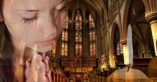 Bild einer betenden Frau in einer imposanten Kirche.