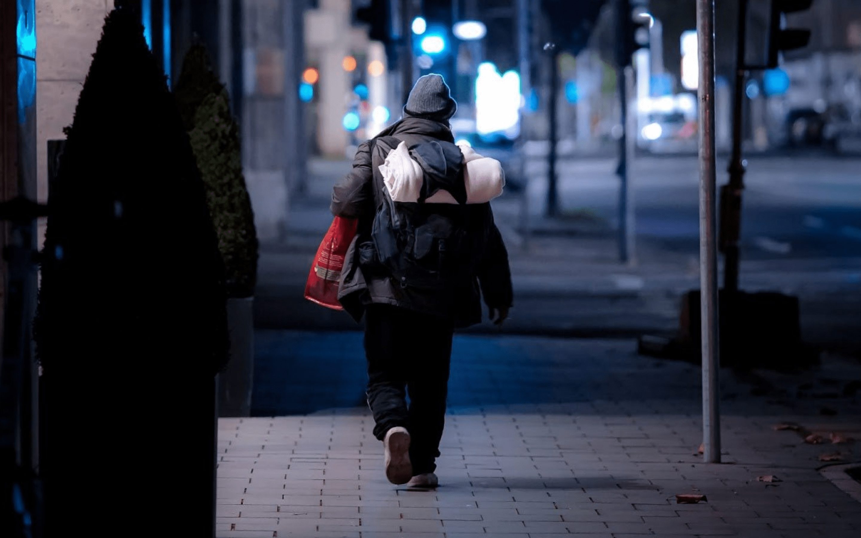 Ein obdachloser Mensch unterwegs auf der Strasse.