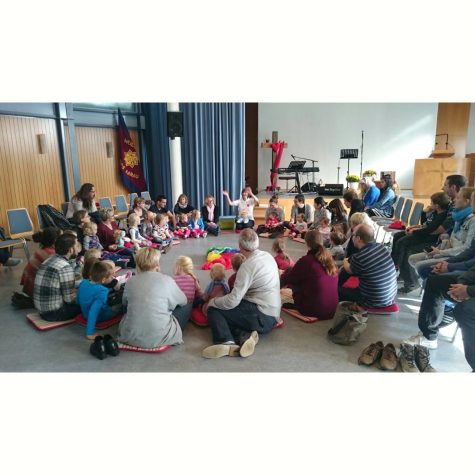 Gruppe von Eltern, Grosseltern und Kindern am Babysong. Die Eltern sitzen mit ihren Kindern in einem Kreis auf dem Boden.