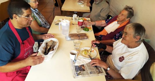 Nabor Rosero von der Heilsarmee sitzt mit Seniorinnen in Renens am Mittagstisch.