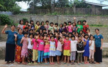 Ein Klassenfoto einer Schulklasse in Myanmar auf dem Schulgelände