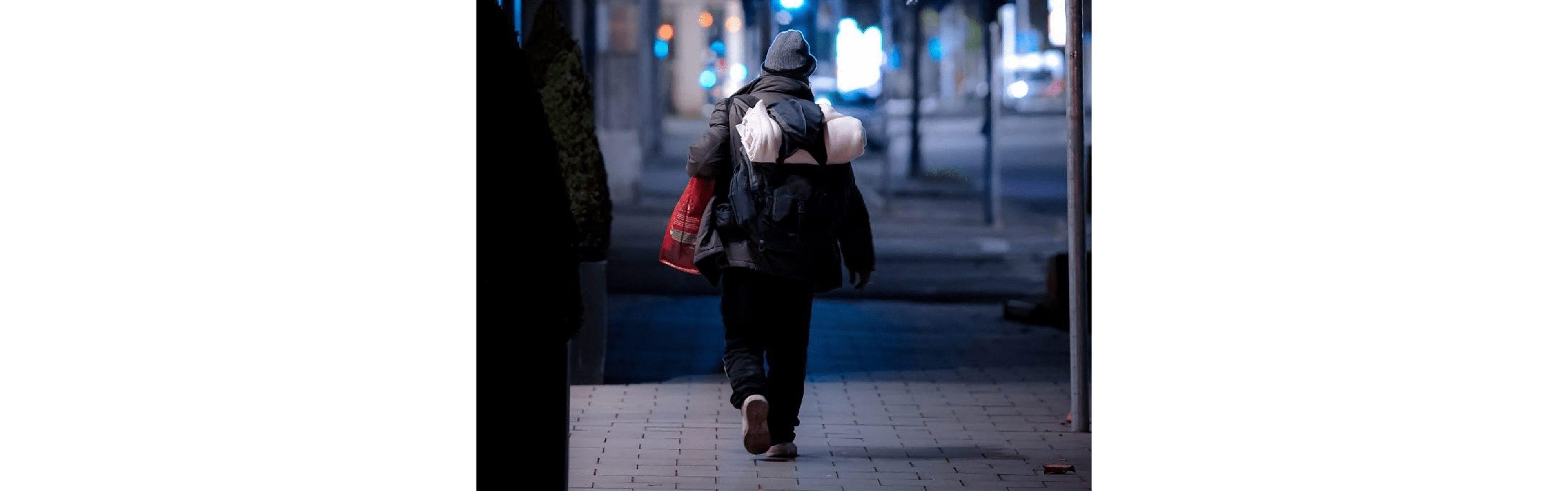 Ein obdachloser Mensch unterwegs auf der Strasse.